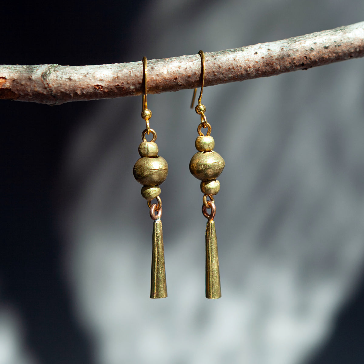 Handmade Ethiopian recycled brass dangle earrings with round beads and long tapered drops in a gold-tone finish.