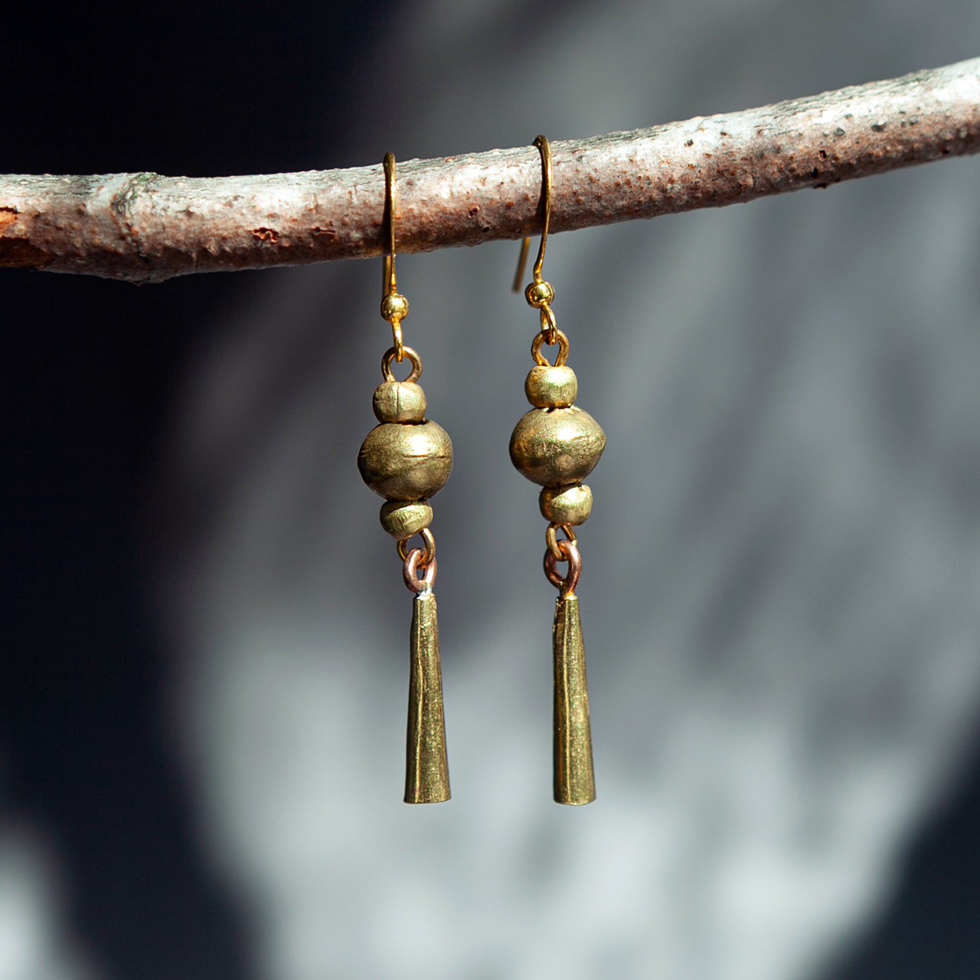 Handmade Ethiopian recycled brass dangle earrings with round beads and long tapered drops in a gold-tone finish.