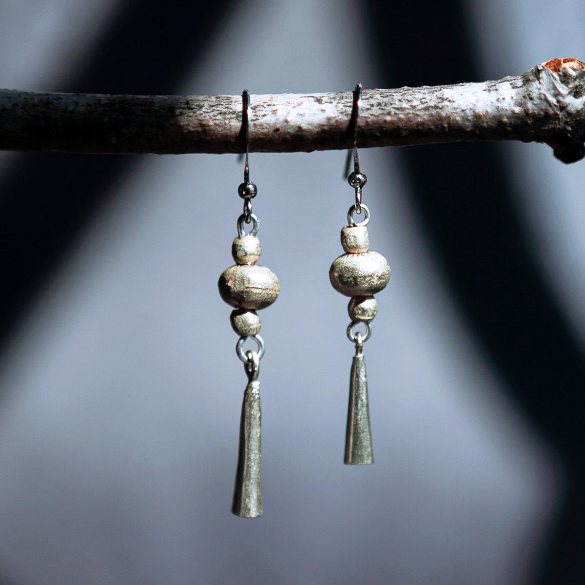 Handmade Ethiopian recycled brass dangle earrings with round beads and tapered drops in a silver-tone finish.