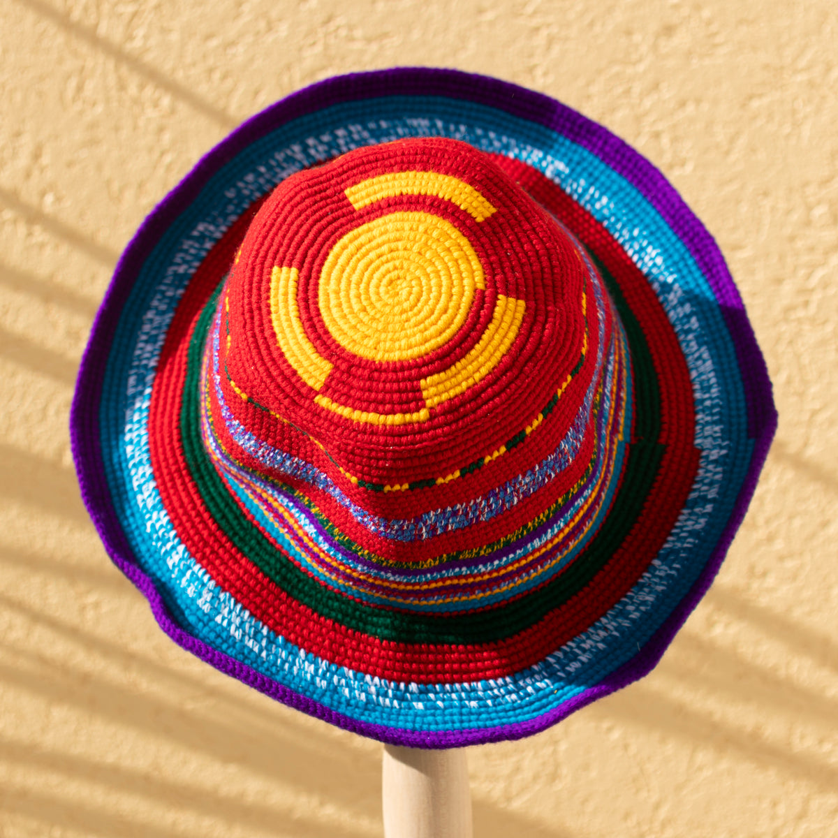 Handmade Konso crochet wide brim hat in red, turquoise, purple, green and yellow with colorful stripes and a purple-trimmed brim.