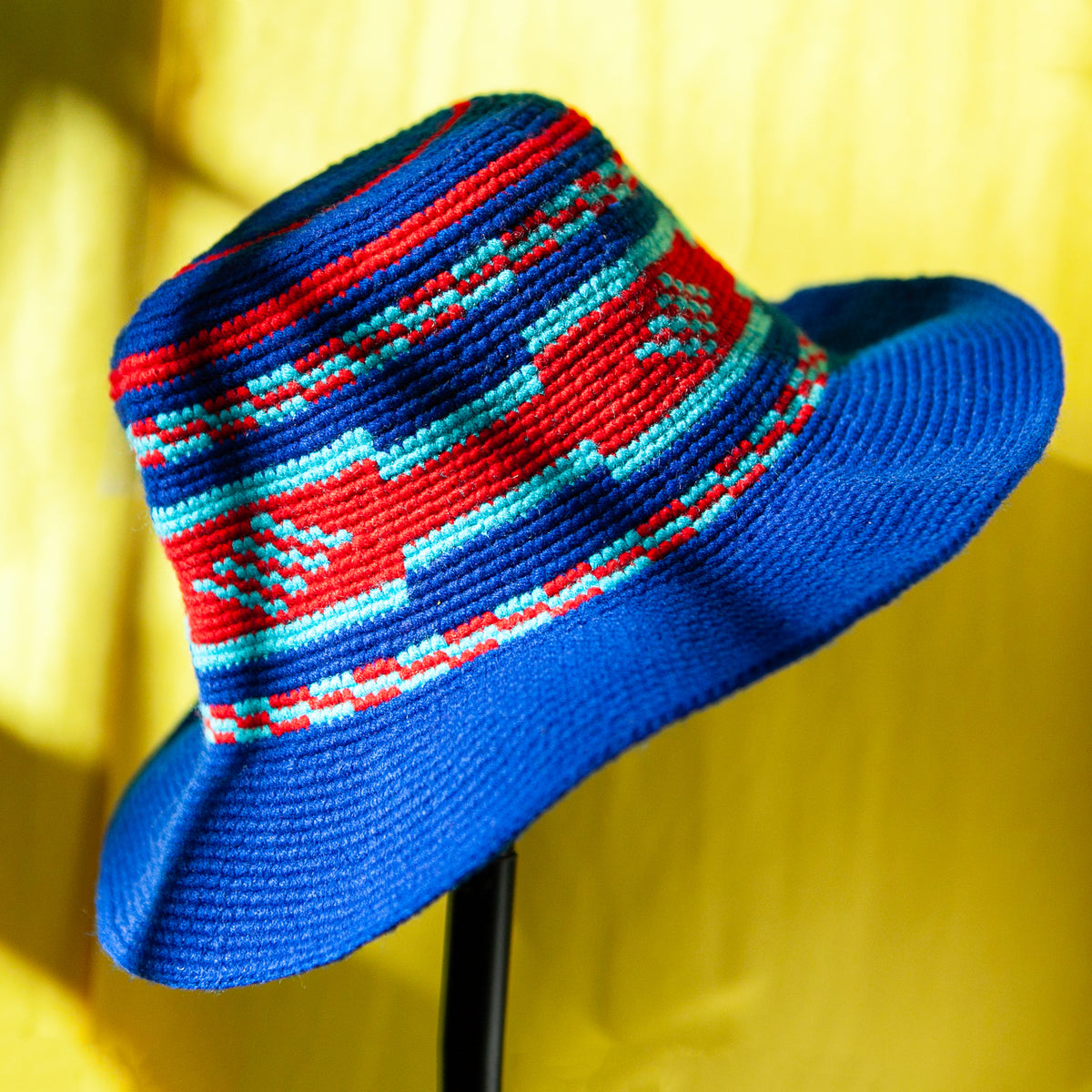 Royal blue Konso crochet wide brim hat handmade in Ethiopia with red and turquoise geometric patterns around the crown.