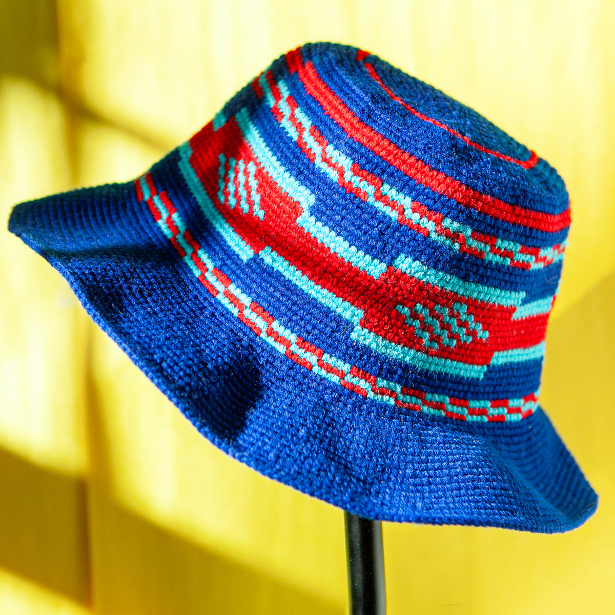 Side view of blue Ethiopian Konso crochet hat showing red and turquoise geometric detailing and structured wide brim.