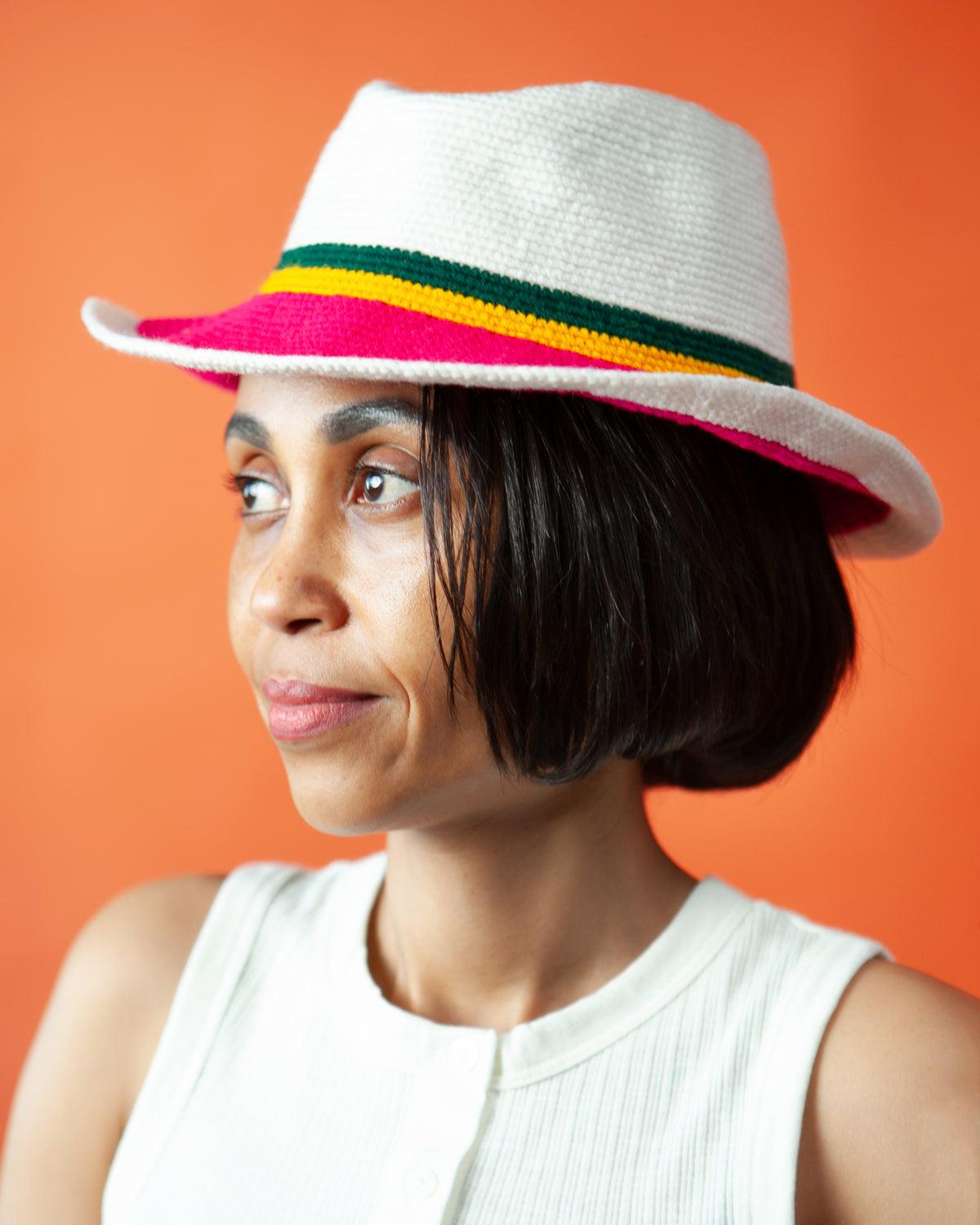 Pink and white handmade Ethiopian Konso crochet fedora showing the wide brim, pink crown detail and green and yellow stripes.