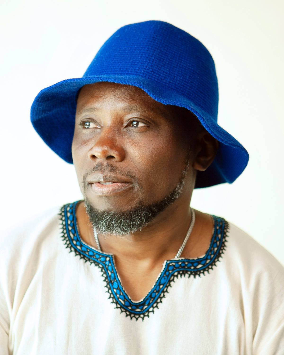 Man wearing a solid royal blue Konso crochet bucket hat handmade in Ethiopia with a wide curved brim.