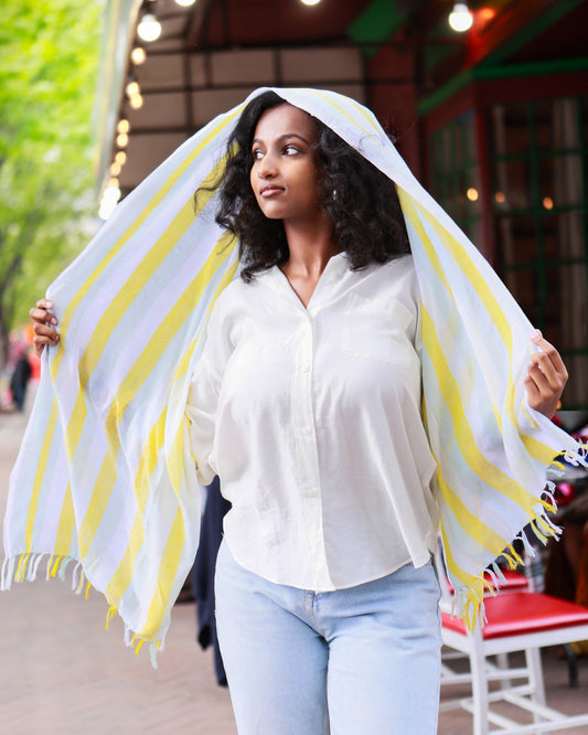 Woman wearing a handwoven yellow and white cotton scarf as a hooded shawl, headscarf, artisan-made in Ethiopia by Kelem